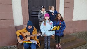 Kinder stehen vor einer Tür und singen